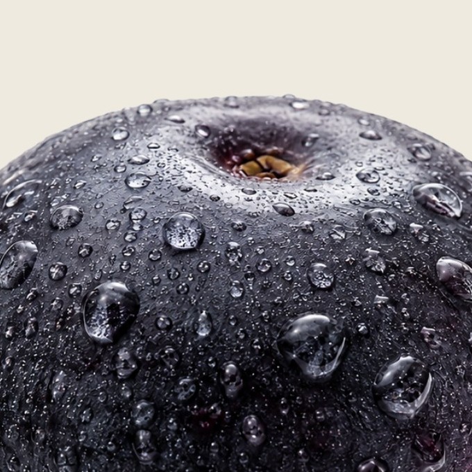 Extreme close-up of a single wet maqui berry, its deep purple-black skin catching the light